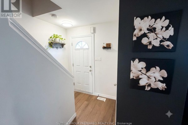 Entryway with white door, dark accent wall with floral art, and staircase. - 27 - 825 Dundalk Drive, London South
