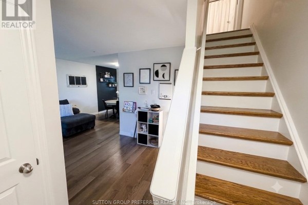 Hallway with hardwood floors, white staircase with wood treads, and entrance to living area. - 27 - 825 Dundalk Drive, London South