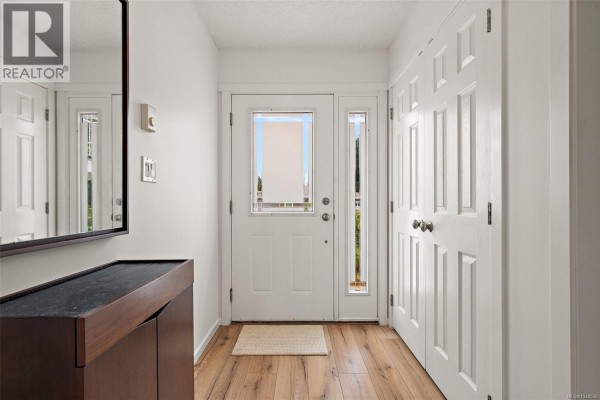 Interior entryway with a white door, sidelight, a dark wood cabinet, and white closet doors. - 27 2740 Stautw Rd, Central Saanich