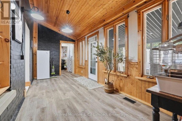 Interior room with wood-paneled ceiling and walls, black brick accent wall, and light gray flooring. - 27 5th Street Nw, Arran Elderslie