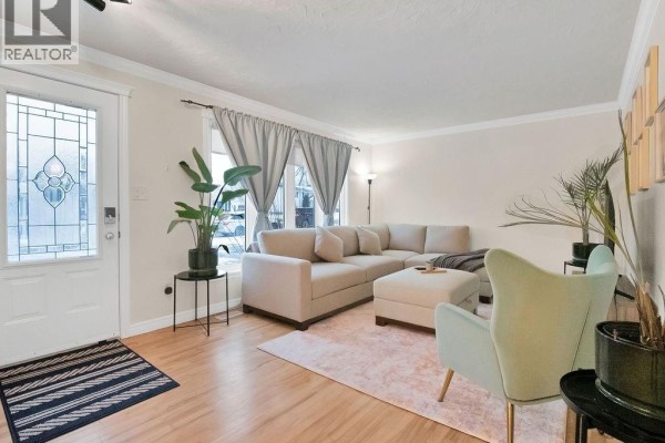 Living room with a sectional sofa, armchair, rug, and a decorative glass door. - 27 Alphonse Street, Shediac