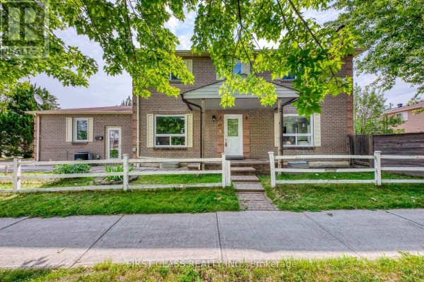 View of the front of the house from the sidewalk, showing the entrance and large windows. - 27 Alton Towers Circle, Toronto