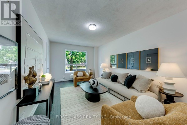 Living room with a view of the outdoors through a large window, featuring a sofa, chairs, and decorative items. - 27 Alton Towers Circle, Toronto