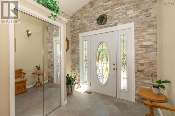 Interior entryway with a stone accent wall, tiled floor, mirrored closet, and a white double door. - 27 Basin View Lane, Upper Clements