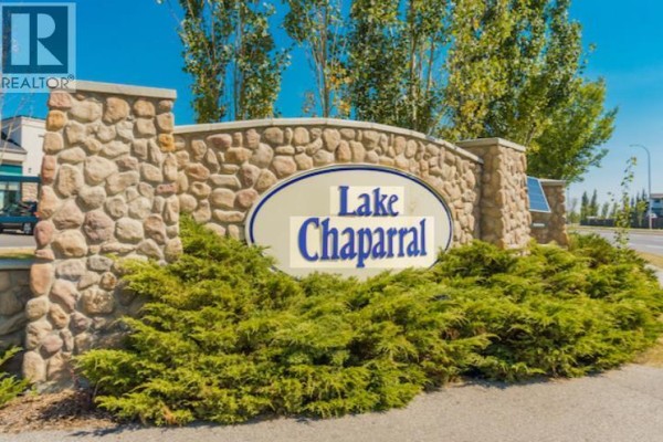 Modern kitchen with white cabinets, a large island with a blue base, quartz countertops, and stainless steel appliances. - 27 Chapman Close Se, Calgary