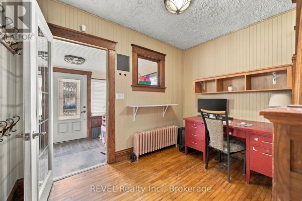 View of a room with a red desk and chair, wood paneling, and a doorway to the exterior. - 27 Christmas Street, Port Colborne