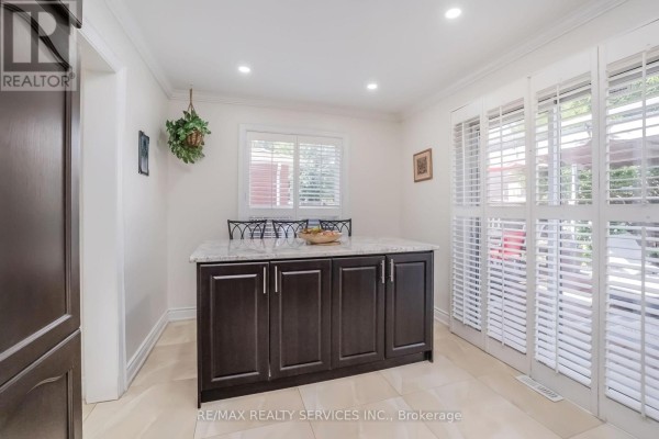 Kitchen island with granite countertop and dark wood cabinets - 27 Colleyville Street Brampton