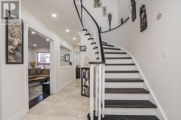 Curved staircase with dark treads and artwork - 27 Colleyville Street Brampton