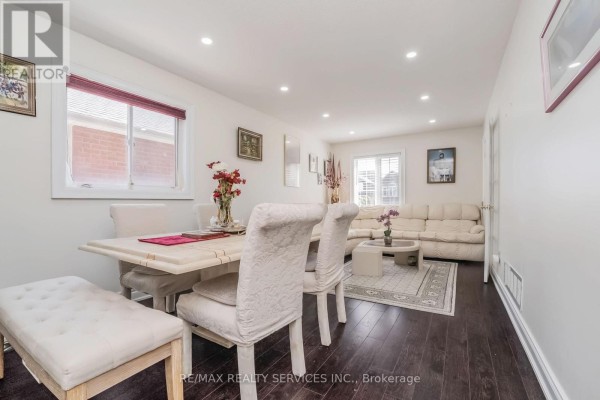 Dining room and living room with sectional sofa, coffee table, and light dining set - 27 Colleyville Street Brampton