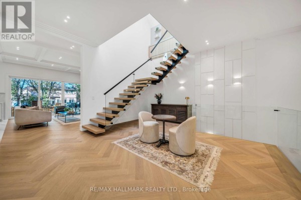 Spacious living area with a floating staircase, wood floors, and seating area. - 27 Collinson Boulevard, Toronto
