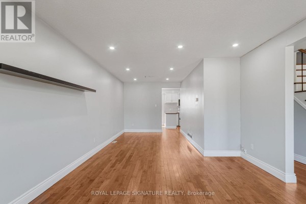 Living room with hardwood floors, recessed lighting, and a view into the hallway and kitchen. - 27 Daphne Crescent, Barrie