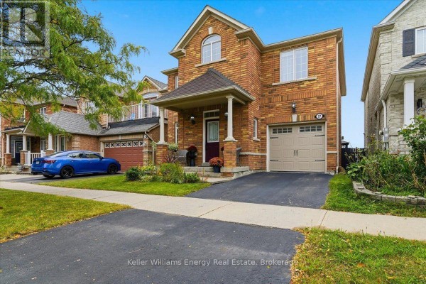 Front view of a brick house with a double garage and a blue car parked on the driveway. - 27 Dent Street, Ajax