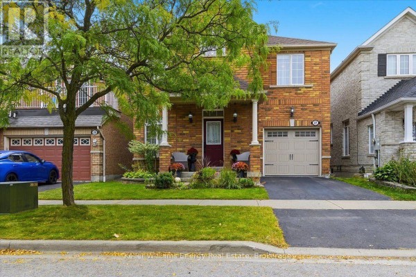 View of a brick house with a covered porch, lawn, driveway, and a blue car parked nearby. - 27 Dent Street, Ajax