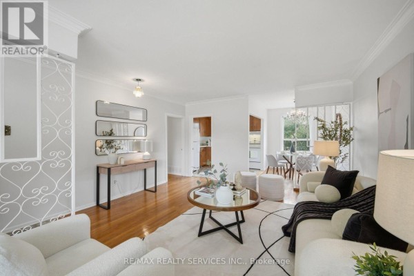 Open concept living and dining area with white furniture and hardwood floors. - 27 Edgemont Drive, Brampton