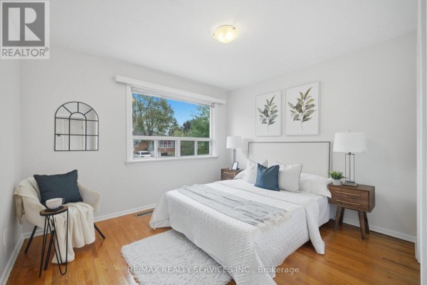 Bedroom with a queen-sized bed, white bedding, and a window view. - 27 Edgemont Drive, Brampton