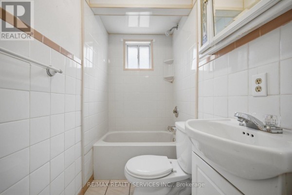 Bathroom with white tile, tub, toilet, and sink - 27 Edgemont Drive Brampton