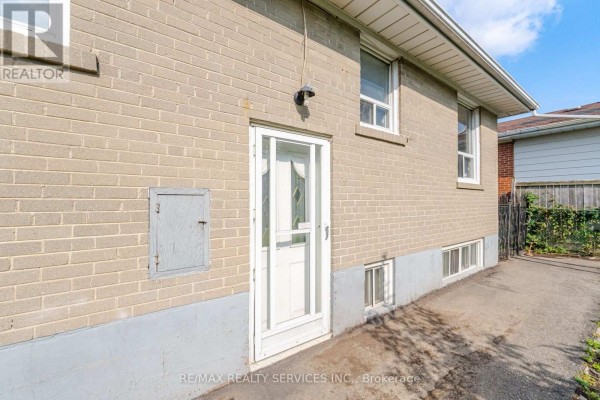 Brick house exterior with storm door and basement windows - 27 Edgemont Drive Brampton