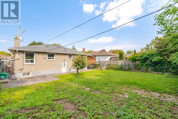 Backyard of brick house with lawn, fence, and swing set - 27 Edgemont Drive Brampton