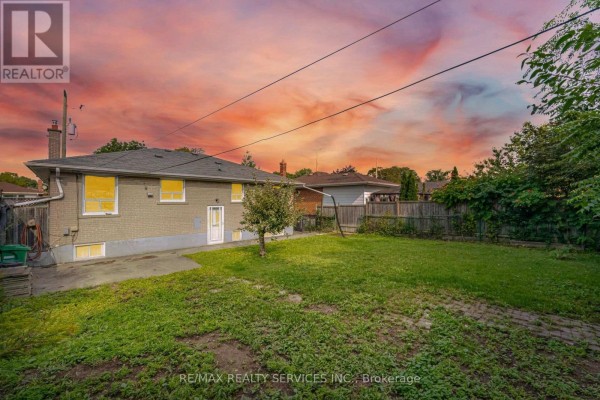 Backyard with fence, grass, tree, and sunset sky - 27 Edgemont Drive Brampton