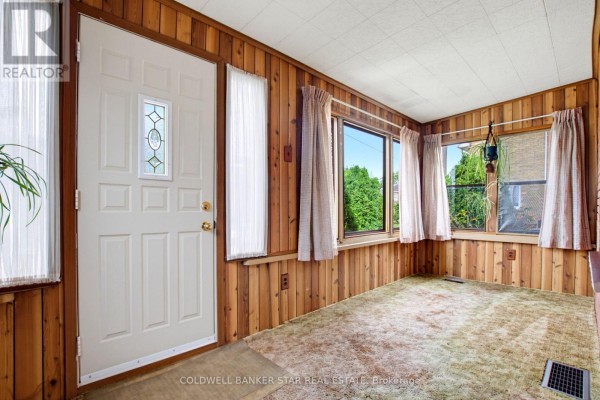 Interior sunroom with wood-paneled walls, a white door, and carpeted floor. - 27 Fourth Avenue, St  Thomas