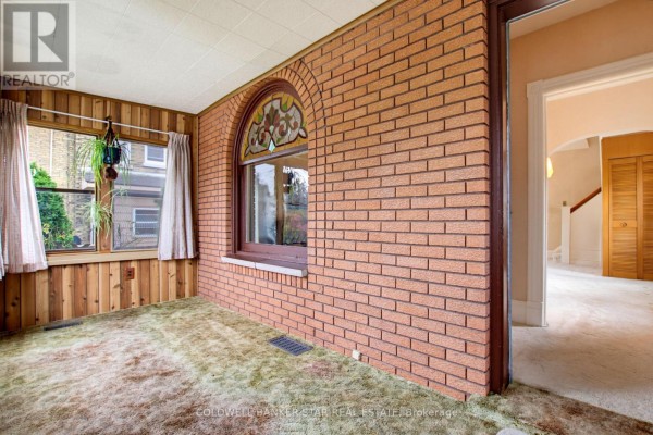 Interior sunroom with brick accent wall, carpet, and view into hallway. - 27 Fourth Avenue, St  Thomas