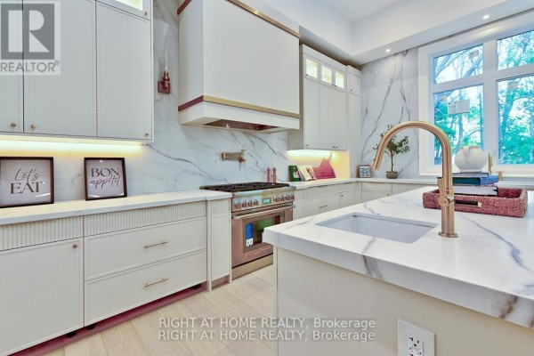 Modern kitchen with marble countertops, gold faucet, and stainless steel range - 27 Hurlingham Crescent Toronto