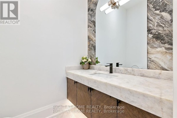 Modern bathroom vanity with marble top, vessel sink, arched mirror, and wood cabinets - 27 Hurlingham Crescent Toronto