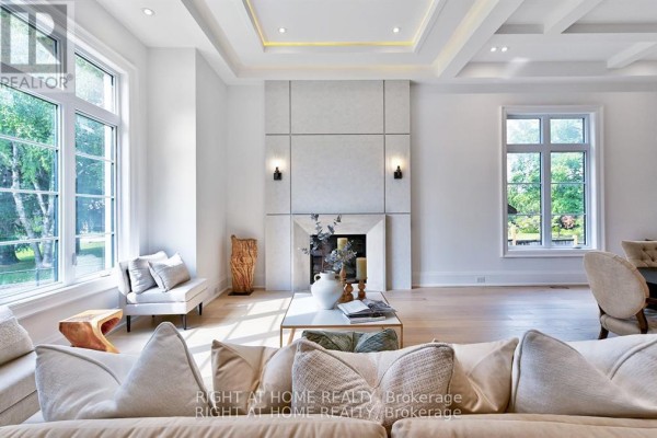 Living room featuring a fireplace, large windows, and a coffered ceiling with accent lighting. - 27 Hurlingham Crescent, Toronto