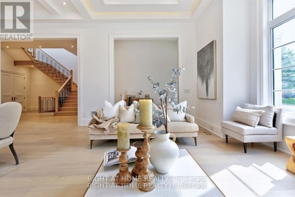 Living room with a beige sofa, coffee table, and a view of the staircase in the background. - 27 Hurlingham Crescent, Toronto
