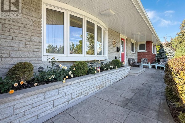 Close-up of the stone exterior and entryway of a house with a flower bed. - 27 Lindbergh Drive, Fort Erie