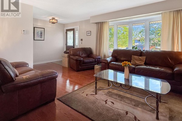 Living room with leather seating, a glass coffee table, wood floors, and view of the front entrance. - 27 Lindbergh Drive, Fort Erie