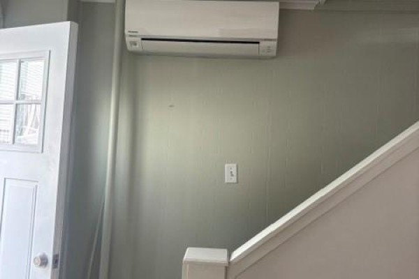 Interior hallway with a white door, staircase, and wall-mounted air conditioning unit. - 27 Mckay Street, St  John S
