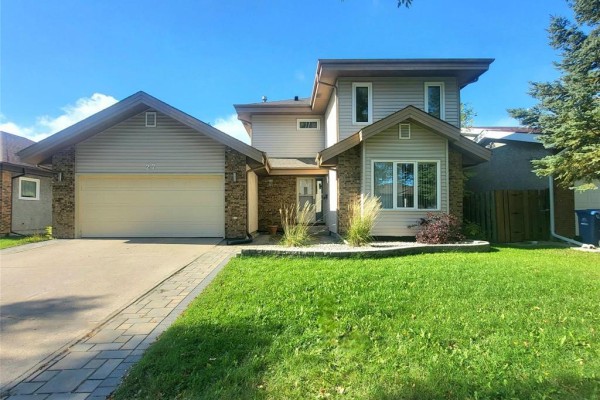 Front exterior of a two-story house with an attached garage, stone and siding facade, and paved walkway. - 27 Olford Crescent, Winnipeg