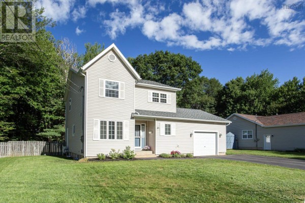 Side-front view of a two-story beige house with a white garage door and green lawn. - 27 Pinecrest Drive, Middleton