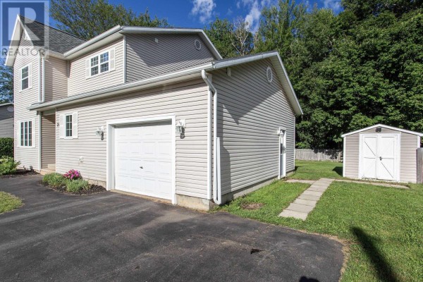 Close-up view of the garage and storage shed of a beige house, with a paved driveway. - 27 Pinecrest Drive, Middleton