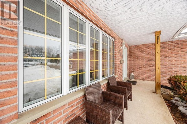 Front porch with brick exterior, large bay window, and wicker chairs. - 27 Plummer Ct, Sault Ste  Marie