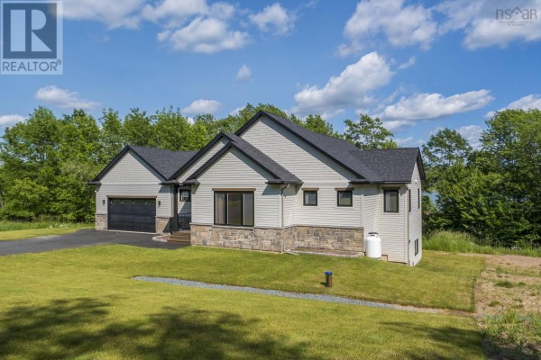 Side view of a modern white house with light grey siding, dark windows, stone foundation, and a propane tank. - 27 Prettybird Lane, Oakfield