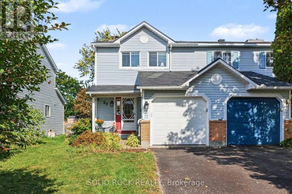 Close-up of the front entrance of a light blue townhouse with a red door and garage. - 27 Randall James Drive, Ottawa