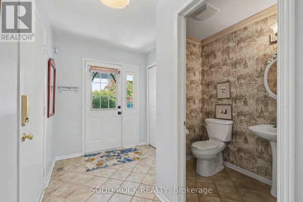 Foyer and doorway to a powder room with patterned wallpaper and white fixtures. - 27 Randall James Drive, Ottawa