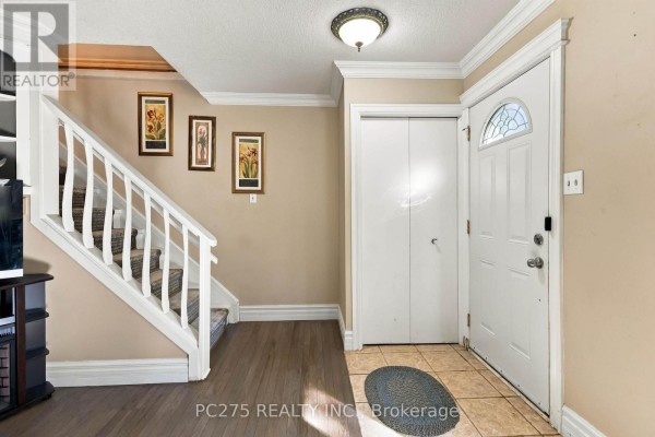 Interior entryway with wood floor, carpeted stairs, white doors, and framed art. - 27 Sasha Crescent, London South