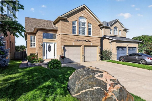 Side exterior view of the brick house with a large decorative rock in the foreground. - 27 Summer Valley Drive, Brampton