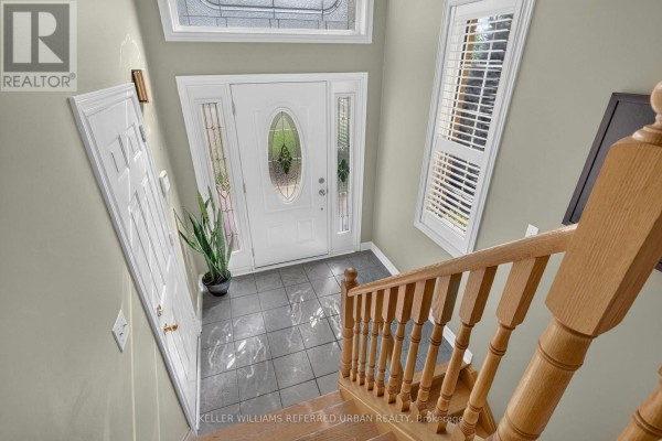 View from the top of the stairs looking down at the tiled foyer and white front door. - 27 Summer Valley Drive, Brampton