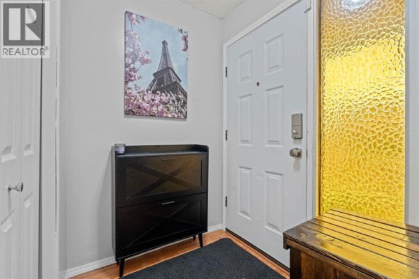 Entranceway with a white door, black shoe cabinet, wood bench, and a framed print. - 27 Templemont Drive Ne, Calgary