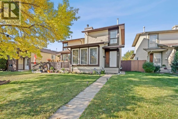 Front exterior of a beige and brown duplex with a pathway and green lawn. - 27 Templemont Drive Ne, Calgary