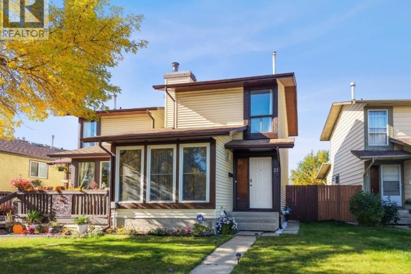 Daytime exterior view of the duplex at 27 Templemont Drive NE with a Canadian flag visible. - 27 Templemont Drive Ne, Calgary