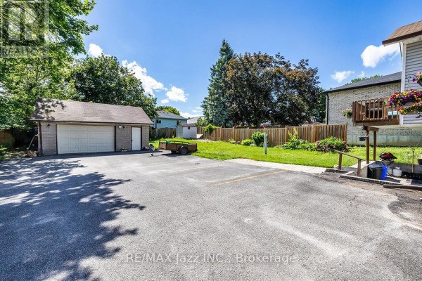 Paved driveway and parking area in front of a detached garage and backyard. - 27 Waverley Road, Clarington