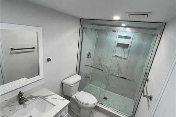 Basement bathroom with a white vanity, toilet, and a glass-enclosed marble tile shower. - 27 William Nador Street Unit# Lower, Kitchener