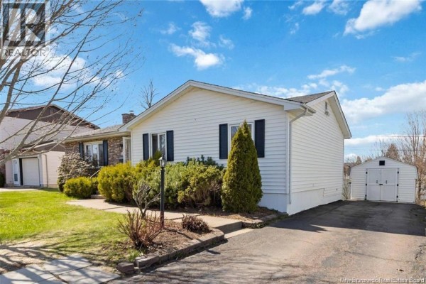 Rear exterior of a white vinyl-sided house featuring a wooden deck with stairs, air conditioning unit, and windows. - 27 Woodstone Crescent, Moncton