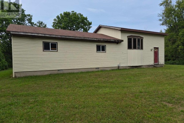 Exterior view of a beige-sided house with a red door and grass lawn. - 270 Edward Street, Saugeen Shores