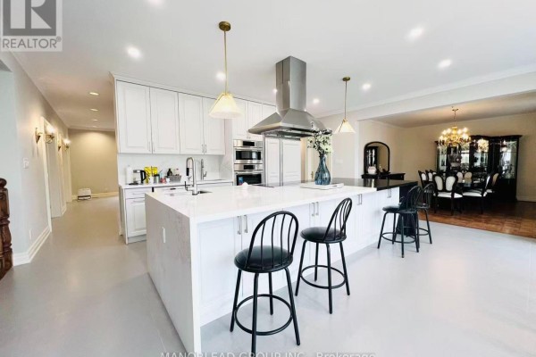 A modern white kitchen with a large island, stainless steel appliances, and pendant lights. - 270 Greenbrooke Drive, Vaughan